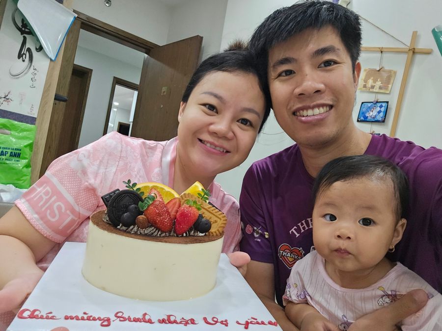 Mum, dad and baby behind a birthday cake with strawberries